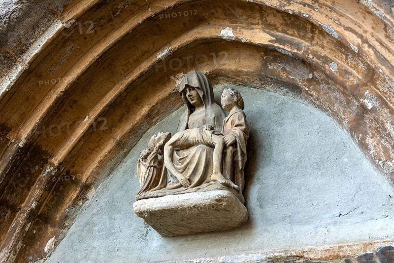 Sculpture of Pieta is prominently displayed above the portal of the church in Collanges, Puy de Dome. Auvergne-Rhone-Alpes. France