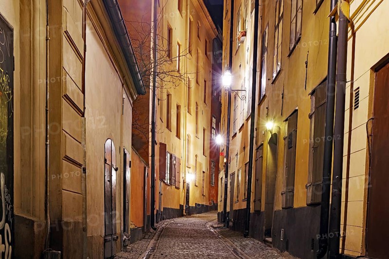 Night shot of a cosy street with old buildings and warm lantern light in a city, winter, Gamla Stan, Old Town, Stockholm Sweden
