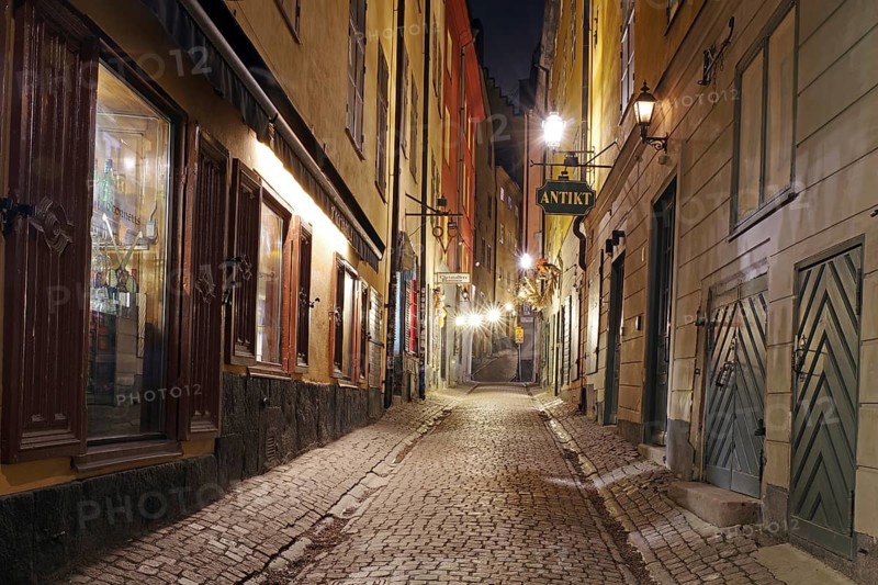 Narrow, illuminated cobblestone alley at night with old charming buildings, winter, Gamla Stan, Old Town, Stockholm Sweden