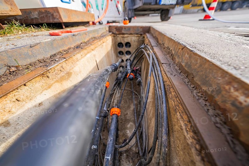 Open manhole with numerous cables and pipes at a construction site, Wend Glasfasermontage installing conduits for fibre optic cables, Meßkirch, Sigmaringen district, Germany, Europe