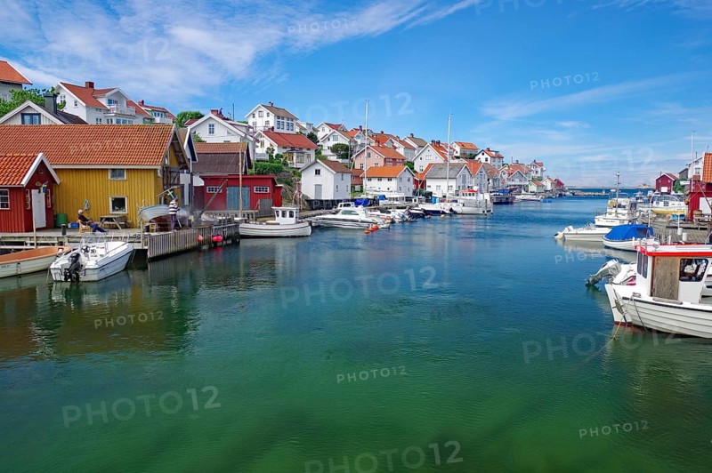 Colourful houses on the water with several boats, under a sunny sky, idyll, crystal clear water, archipelago, Gullholmen, Västra Götalands län, Sweden, Europe