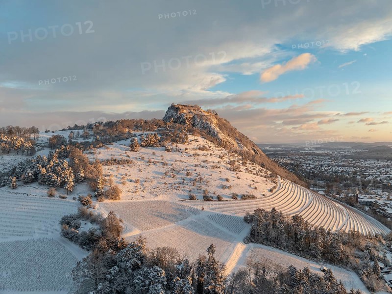 Aerial view of the snow-covered Hegau volcano Hohentwiel with Germany's largest castle ruins on a cold winter morning, at sunrise, in front of it Germany's highest vineyard, the Elisabethenberg at 505 metres above sea level, on the right the town of Singen, district of Constance, Baden-Württemberg, Germany, Europe