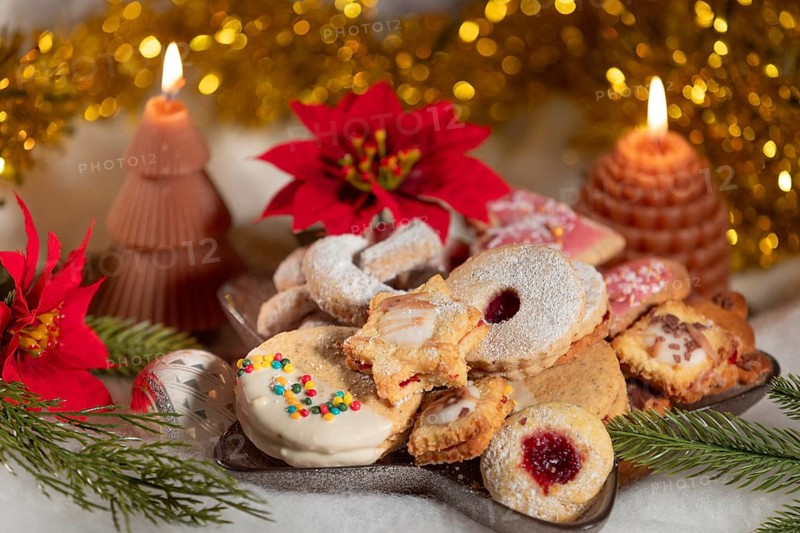A plate full of biscuits surrounded by candles and red poinsettias