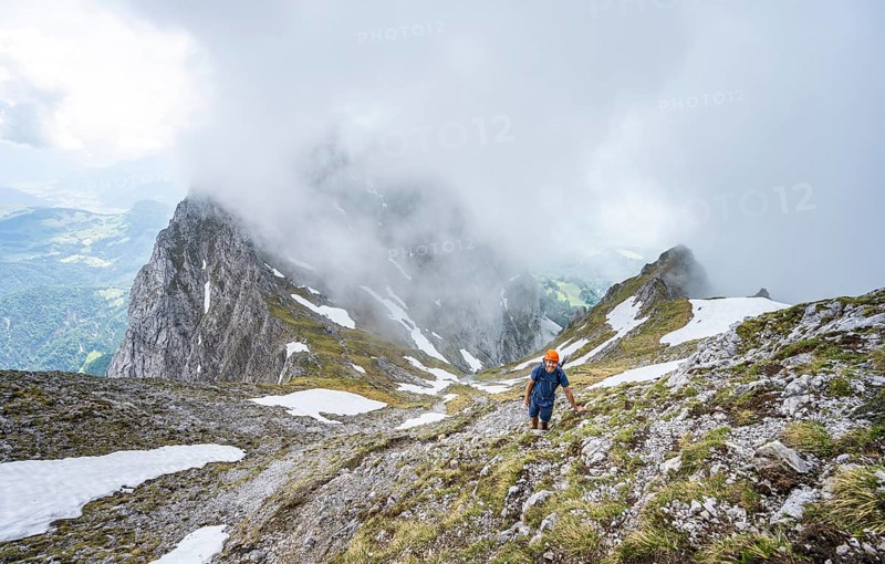 Mountaineer with helmet on a narrow hiking trail, ascent to the Ackerlspitze, clouds moving around the mountains, Wilder Kaiser, Kaiser Mountains, Tyrol, Austria, Europe