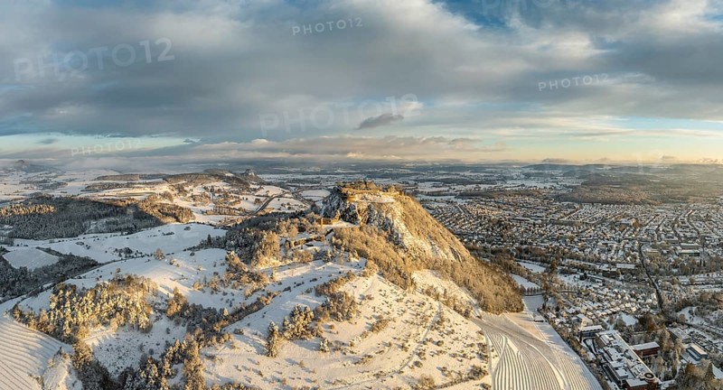 Aerial view, panorama of the snow-covered Hegau volcano Hohentwiel with Germany's largest castle ruins on a cold winter morning, at sunrise, on the right the town of Singen, on the left on the horizon the neighbouring Hegau volcano Hohenkrähen, district of Constance, Baden-Württemberg, Germany, Europe