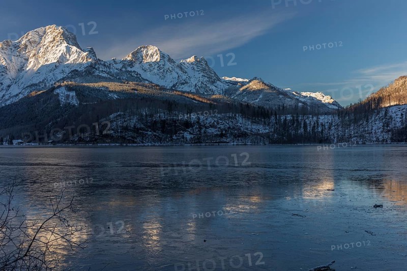 Lake Almsee in winter. Snow on the mountains and a clear blue sky. Perfect reflection on the lake