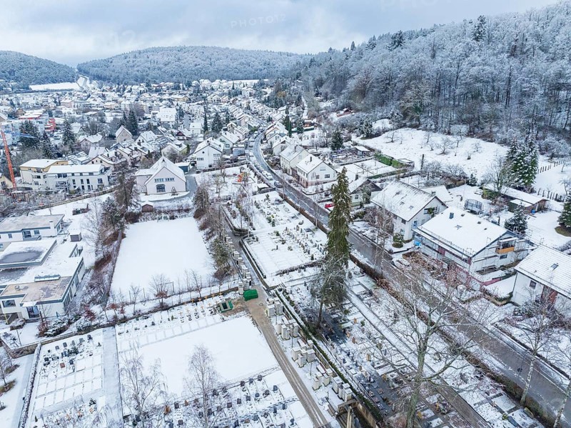 Snow-covered landscape of a village with houses, trees and a cemetery in winter, Aidlingen, Böblingen district, Germany, Europe