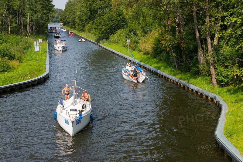 Boats glide along a tree-lined canal surrounded by summer nature, Gizycko, Warminsko-Mazurskie, Warmia-Mazurskie, Poland, Europe