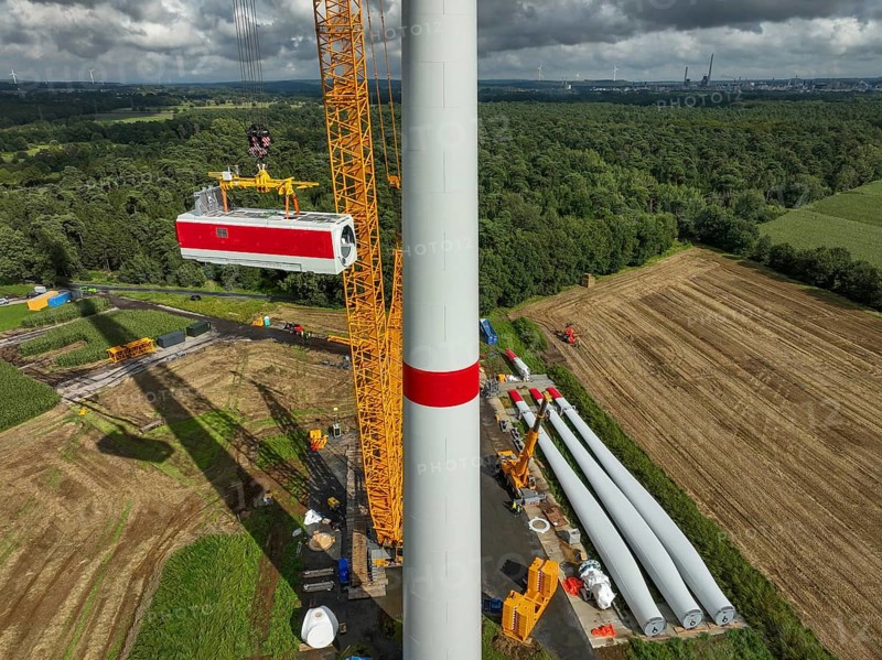 Dorsten, North Rhine-Westphalia, Germany, construction of a wind turbine, the first wind turbine of the Große Heide wind farm. A large mobile crane places the nacelle, the nacelle on the tower. The rotor blades, vanes and rotor hub are ready for assembly, Europe