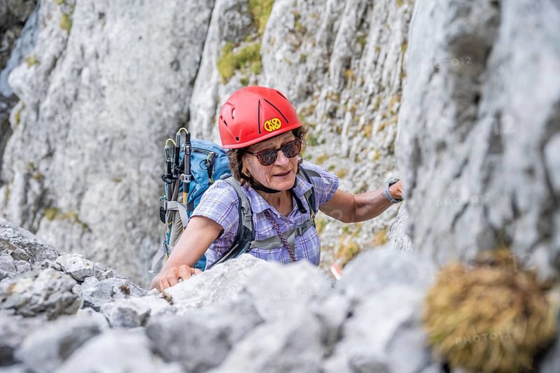 Female mountaineer with helmet climbing a rock face, ascent to the Ackerlspitze, Wilder Kaiser, Kaiser Mountains, Tyrol, Austria, Europe