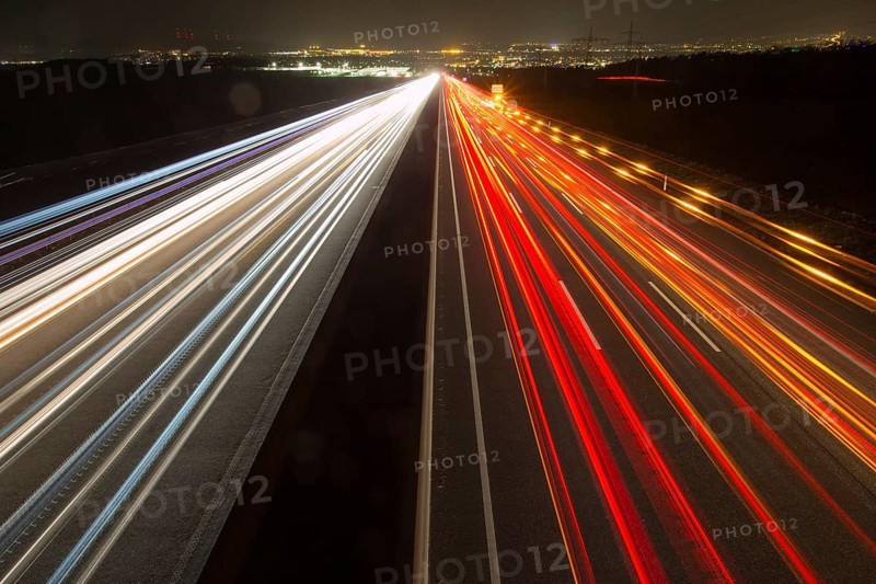 A7 Motorway, Autobahn, beside Kassel at night with light trails from the traffic headlights and taillights and the full moon rising in the distance, Hesse, Germany, Europe