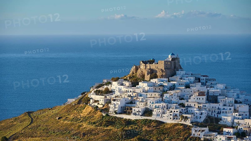 Panorama with white buildings on a hill, dense waves surrounding an old fortress by the sea, Querini Castle, Chora, Astypalea, Dodecanese, Greek Islands, Greece, Europe