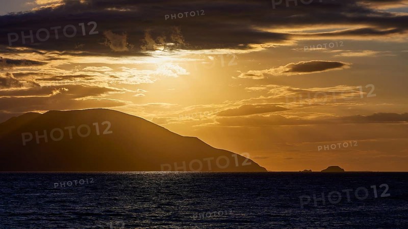 The sky shows a dramatic sunset with dark clouds and an island on the horizon, sunset, Kassos, Karpathos, offshore islands, Dodecanese, Greek Islands, Greece, Europe