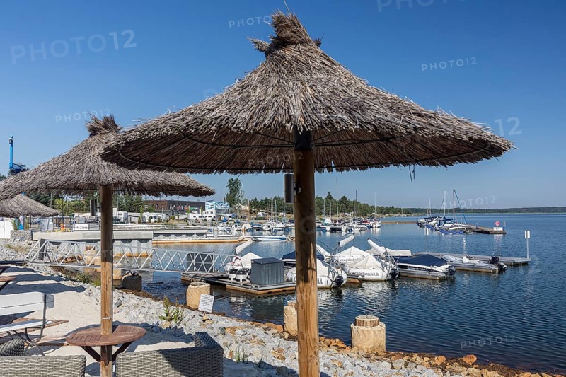 Straw parasols with a view of the harbour of Lake Geierswalde, Geierswalde in the Lusatian Lakeland, Saxony, Germany, Europe