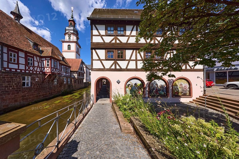 River Mümling, half-timbered houses, archway, church tower, metal railing, flower bed, blue sky with cumulus clouds, main street, Erbach, Odenwald, Odenwaldkreis, Hesse, Germany, Europe