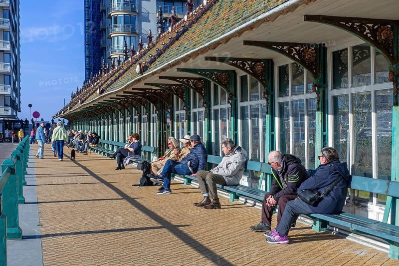 Tourists sunbathing on a sunny spring day under the Paravang, windbreak dating from the Belle Epoque at Blankenberge, West Flanders, Belgium, Europe
