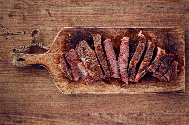 Medium rare, sliced rib eye steak, grilled cowboy steak, on a chopping board, close-up, homemade, top view, no people