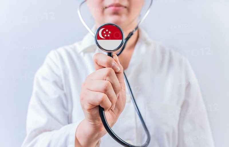 Doctor holding stethoscope with Singapore flag. National Health System of Singapore