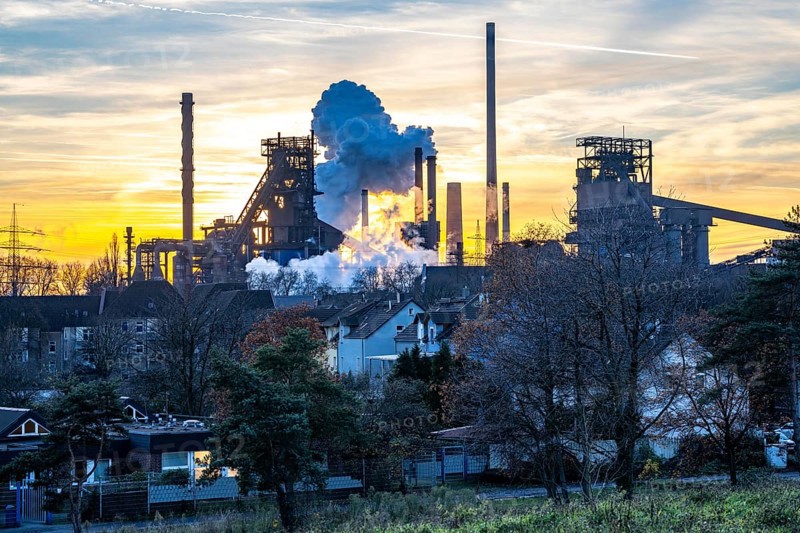Blast furnace Schwelgern 1, Black Giant, Schwelgern 2 ThyssenKrupp Steel plant Schwelgern in Duisburg-Marxloh is part of the Bruckhausen steelworks, residential buildings in the Marxloh district, extinguishing cloud from the Schwelgern coking plant, sunset, North Rhine-Westphalia, Germany, Europe