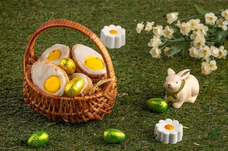 Easter biscuits in baskets with a bunny figure and flowers on a green lawn