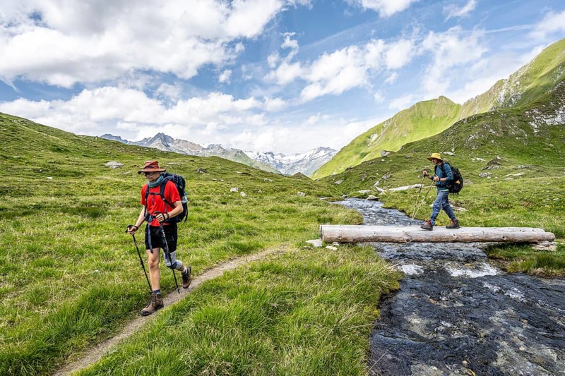 Two mountaineers crossing a stream on a tree trunk, mountain landscape with mountain stream, Lasörling Group, Hohe Tauern National Park, East Tyrol, Austria, Europe