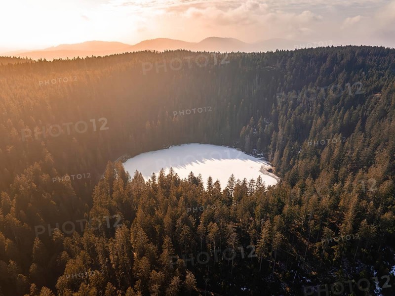 Aerial view of a circular lake in the midst of wintry fog and forest landscapes, Glaswaldsee, Bad Rippoldsau-Schapbach, Black Forest, Germany, Europe