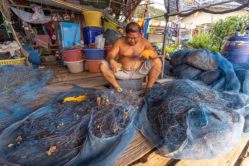 Fisherman repairing his net, fishing village Ban Ao Salad, island Ko Kut or Koh Kood in the Gulf of Thailand