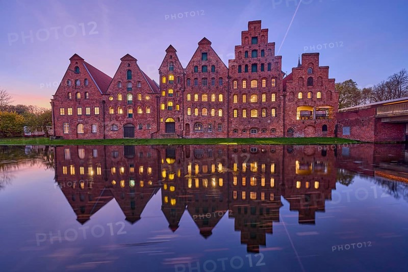 Historic salt warehouses, brick buildings, illuminated windows, symmetrical reflections on the water surface, blue hour in the evening, Hanseatic city of Lübeck, independent city, Schleswig-Holstein, Germany, Europe