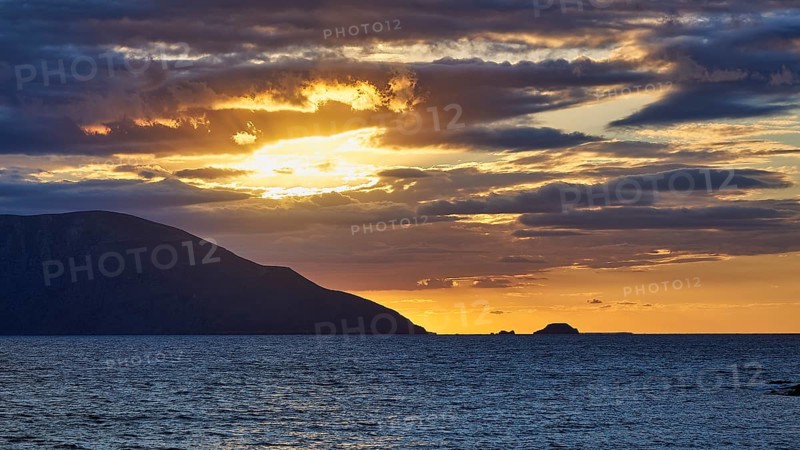 A dramatic sunset with clouds over the sea, an island on the horizon at dusk, sunset, Kassos, Karpathos, offshore islands, Dodecanese, Greek Islands, Greece, Europe