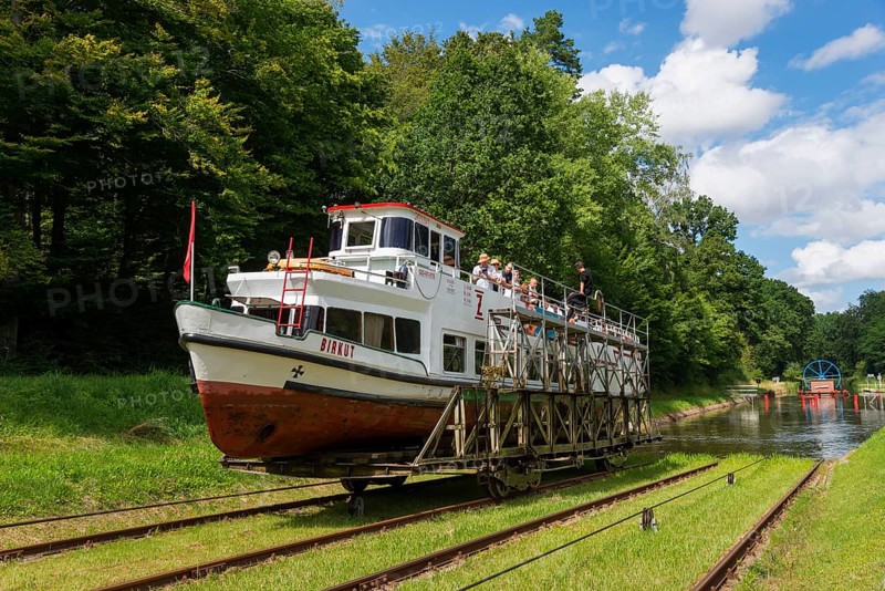 A boat being transported overland on a railway wagon, surrounded by forest and blue sky, ship Birkut, Buchwalde, Buczyniec, Upland Canal, Warminsko-Mazurskie, Poland, Upland Canal, Elbling Osterode Canal, Elblag-Ostroda Canal, Warminsko-Mazurskie, Poland, Europe