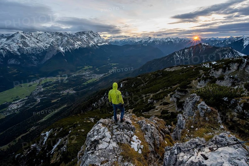View Mountain panorama with Wetterstein mountains and Zugspitze, at sunset with sun star, mountaineer at the summit of the Kramerspitz, in autumn, Ammergau Alps, in autumn, Bavarian Prealps, Bavaria, Germany, Europe
