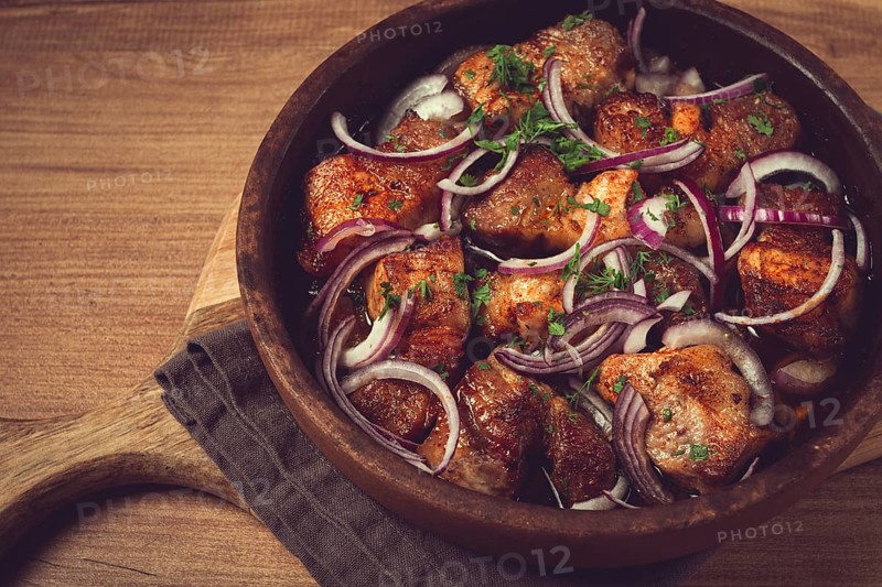 Fried meat, pork kebab, ketsi in a clay pan, with red onions and herbs, homemade, no people