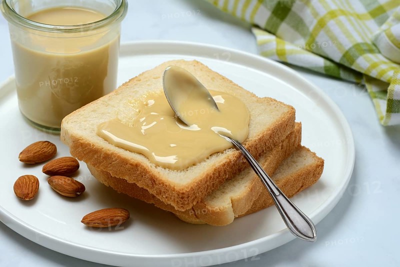 Almond cream on toast, almonds and spoon