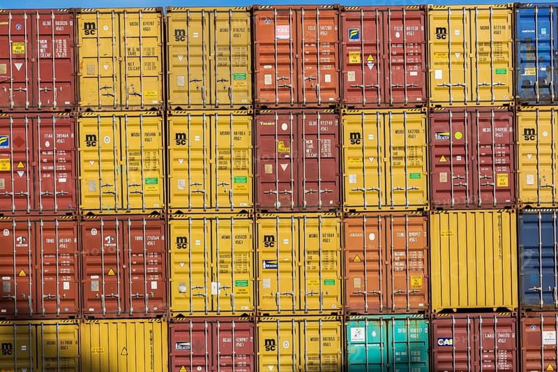 Rows of stacked yellow, reddish brown, blue, orange and turquoise metal box shipping containers on dock in La Spezia cargo Port, Italy, Europe