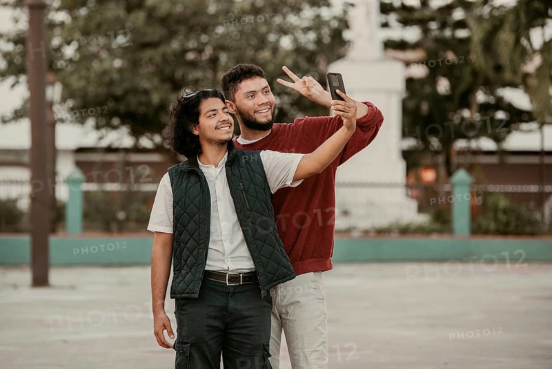Two male friends taking a selfie on the street. Portrait of funny friends taking a selfie on the street