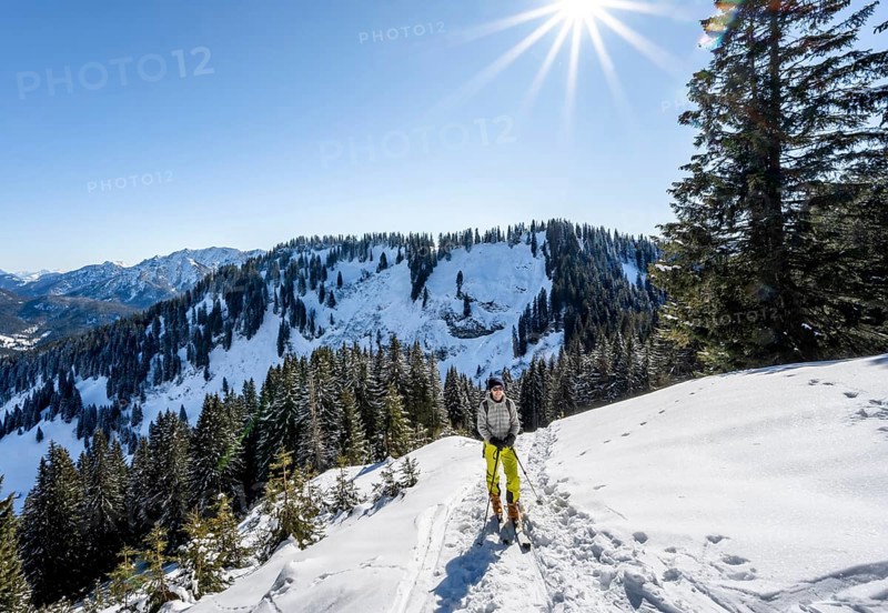 Ski tourer in wintry mountain landscape with sun star, ascent to Roßkopf, Mangfallgebirge, Bavaria, Germany, Europe
