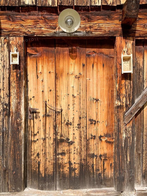 Entrance door of a rustic old weathered alpine hut decorated with butter moulds, East Tyrol, Austria, Europe