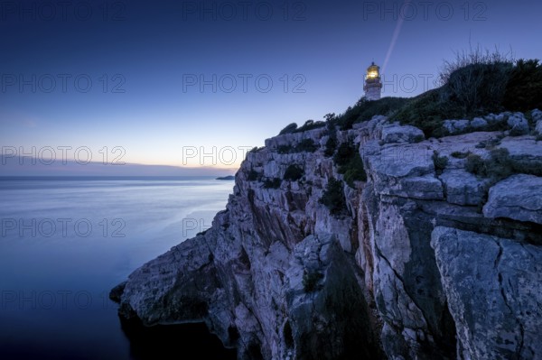 Lighthouse on cliffs overlooking the calm sea at dusk, Lastovo, Neretva, Croatia, Europe