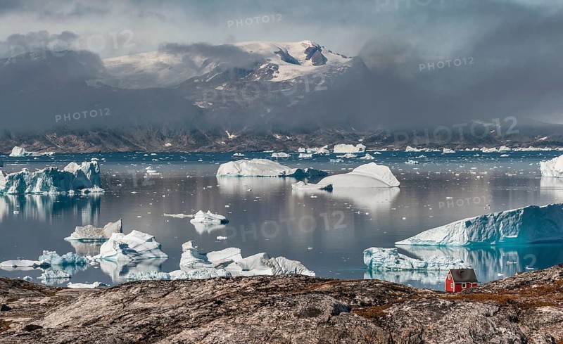 Large icebergs floating in a fjord behind a red wooden house, Inuit settlement Tiniteqilaaq, Sermilik Fjord, East Greenland, Greenland, North America