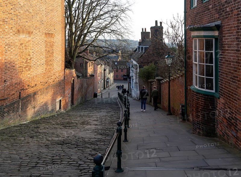 People walking on Steep Hill in evening light, Lincoln, Lincolnshire, England, UK