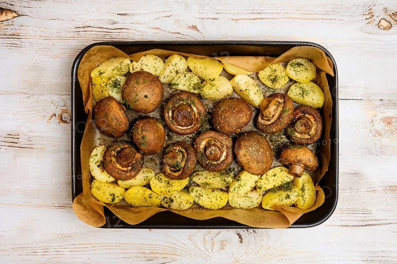 Champignon mushrooms and tender potatoes are seasoned with herbs and roasted to perfection on a baking tray, creating a delicious meal