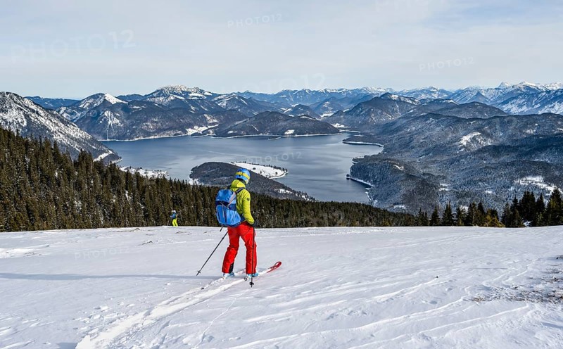 Skiers skiing down the Simetsberg, view of Walchensee and mountain panorama, Estergebirge, Bavarian Prealps, Bavaria Germany