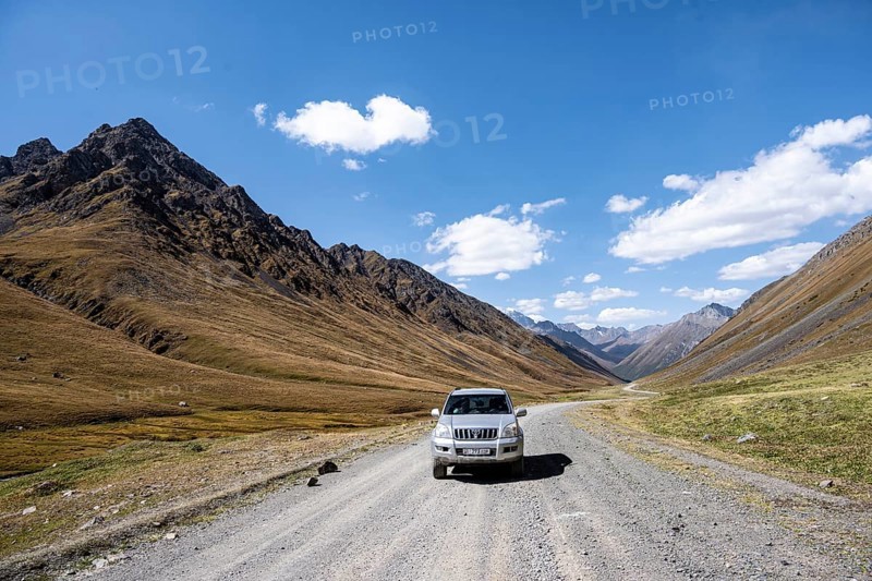 Off-road vehicle driving on a gravel track in a valley, picturesque mountain landscape with white mountain peaks, Tian Shan Mountains, Issyk-Kul, Kyrgyzstan, Asia