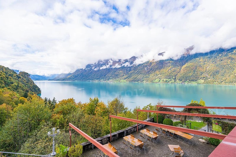 View of a lake with surrounding mountains and a terrace with tables, Lake Brienz, Switzerland, Europe