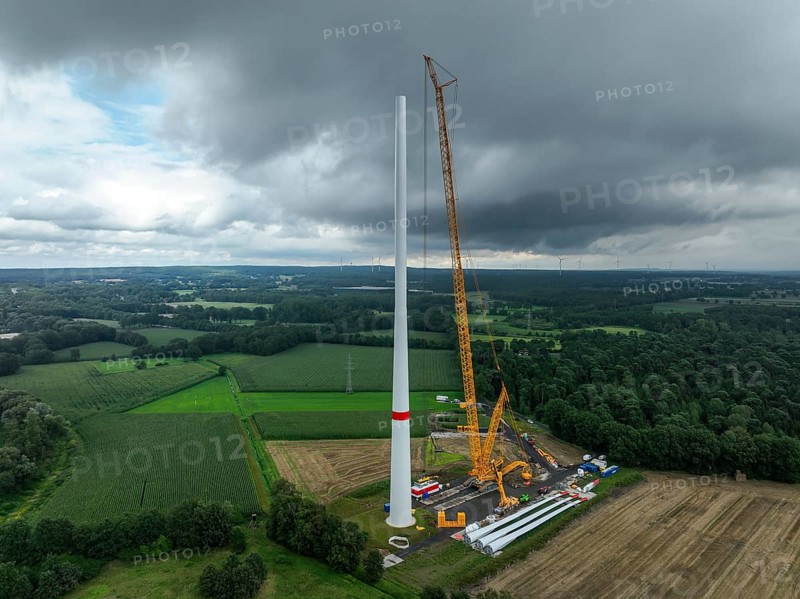 Dorsten, North Rhine-Westphalia, Germany, construction of a wind turbine, the first wind turbine of the Große Heide wind farm. A large mobile crane places the nacelle, the nacelle on the tower. The rotor blades, vanes and rotor hub are ready for assembly, Europe