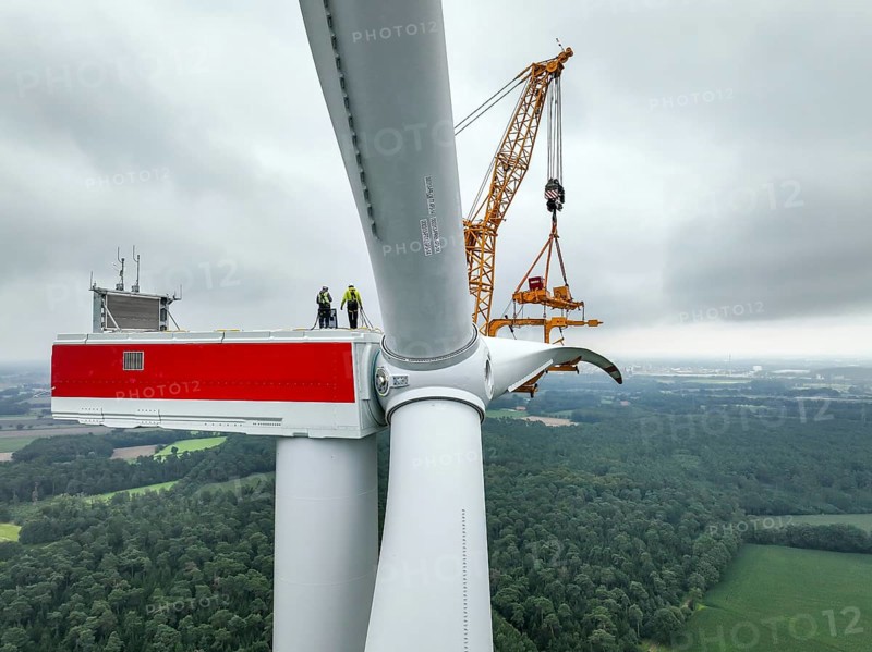 Dorsten, North Rhine-Westphalia, Germany, construction of a wind turbine. A large mobile crane lifts a rotor blade to the nacelle on the tower. Here, the blade is mounted directly on the motor hub. Große Heide wind farm, Europe