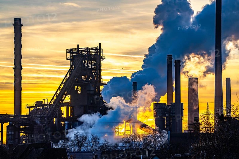Blast furnace Schwelgern 1, Black Giant, ThyssenKrupp Steel plant Schwelgern in Duisburg-Marxloh belongs to the Bruckhausen steelworks, extinguishing cloud of the Schwelgern coking plant, sunset, North Rhine-Westphalia, Germany, Europe
