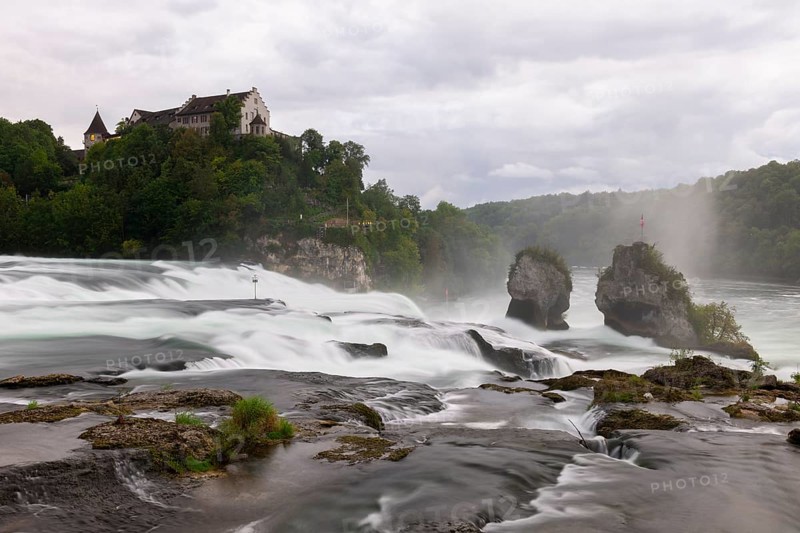 Dramatic waterfall flows past rocks to a castle, Schloss Laufen, Rhine Falls, Canton Schaffhausen, Switzerland, Europe