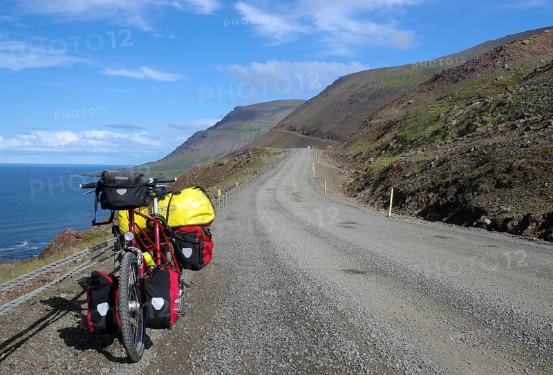 Lonely bike with panniers on a gravel road along the coast with sea and mountains, cycle tour, cycle tourism, Dalvik, Iceland, Europe