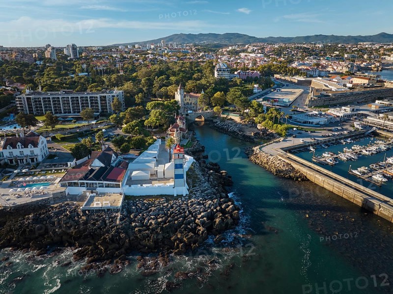Aerial view of Santa Marta lighthouse and Cascais marina with moored yacht boats with Cascais cityscape, Portugal on sunset